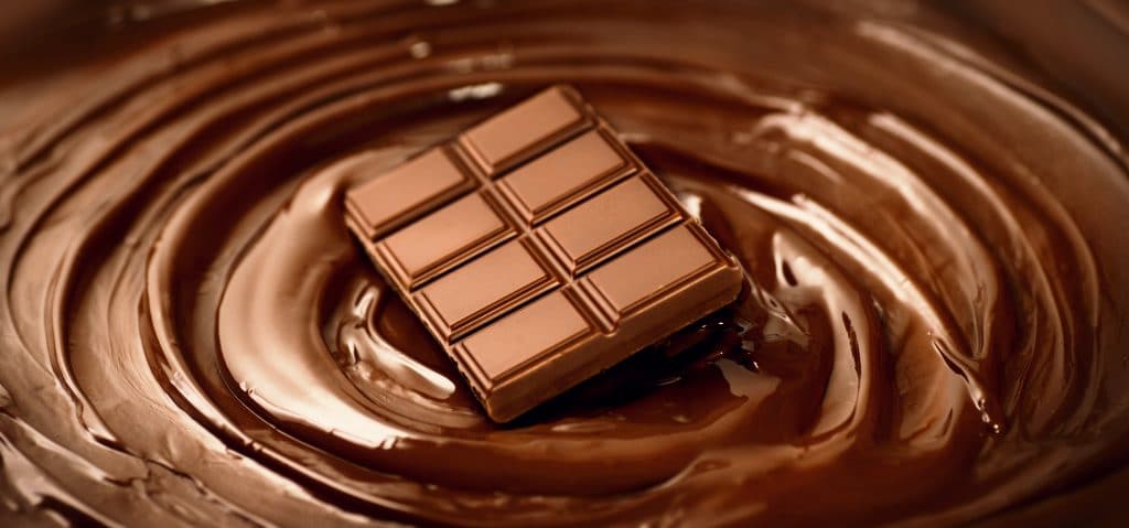 Barra de chocolate sobre o fundo de um mousse de chocolate derretido.