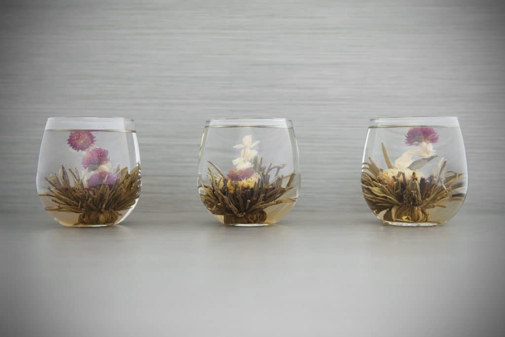 Três canecas de vidro com chá de Alforva. Os copos estão decorados com a flor da planta.