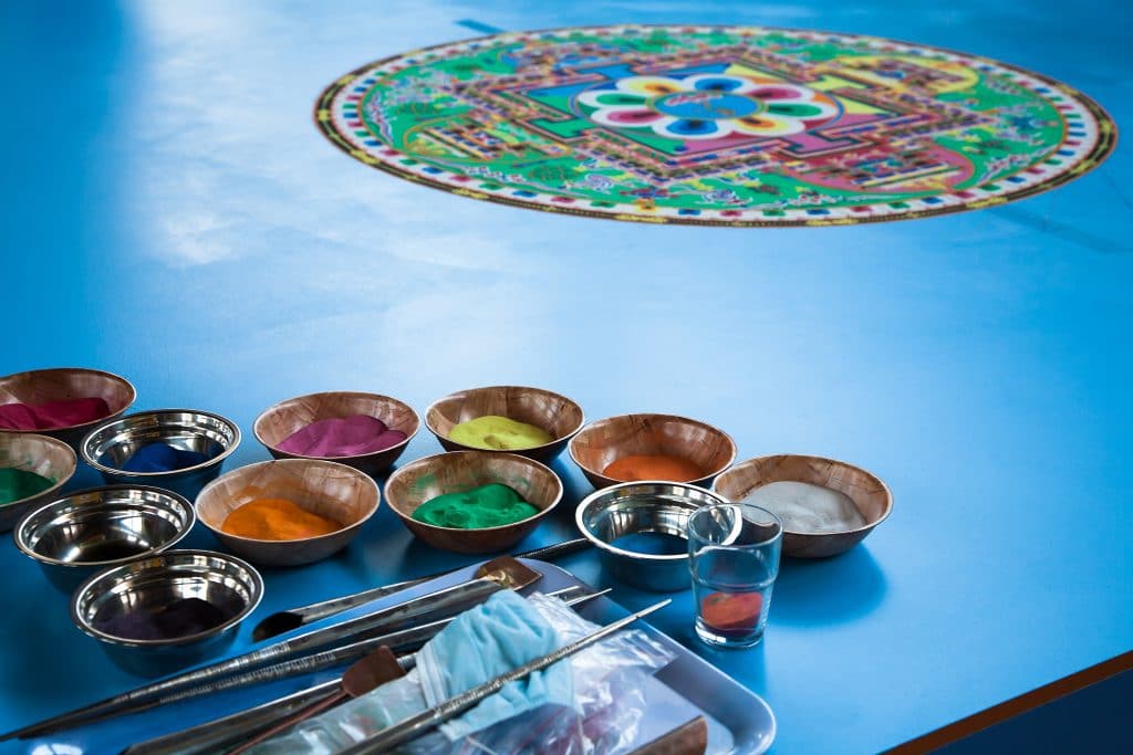 Criação de uma mandala colorida. El está sendo desenvolvida em uma mesa azul.