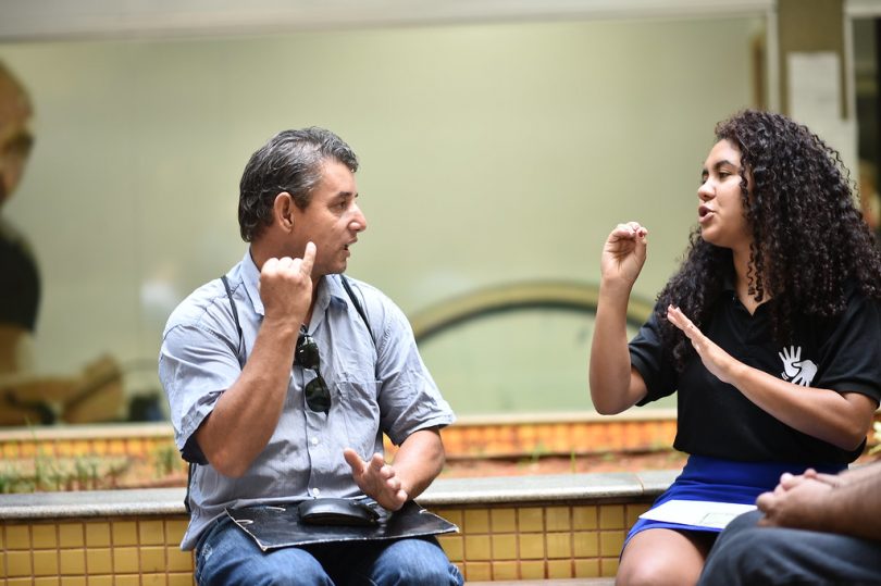 Homem se comunica com menina através da linguagem brasileira de sinais (libras).