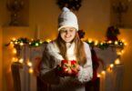 Mulher segurando presente de natal em casa enfeitada com luzes