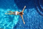 Mulher de biquíni branco nadando na piscina.