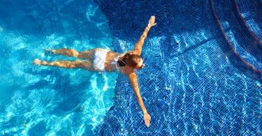 Mulher de biquíni branco nadando na piscina.