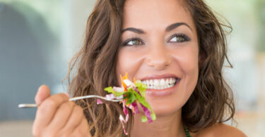 Mulher segurando um garfo com salada