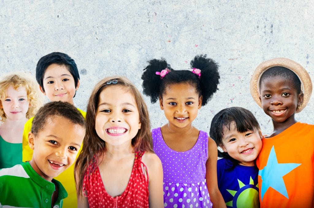 Muitas crianças de várias raças e nacionalidades. Todas elas estão felizes e sorrindo.
