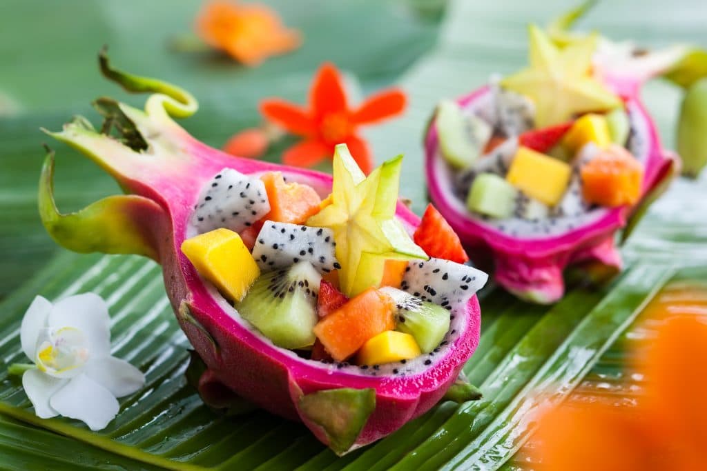 Salada de frutas bem saborosa servida dentro da fruta pitaya.
