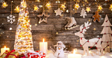 Decoração de Natal toda em miniatura, com árvore iluminada, caixas de presentes, boneco de neve, rena, estrelas e velas.