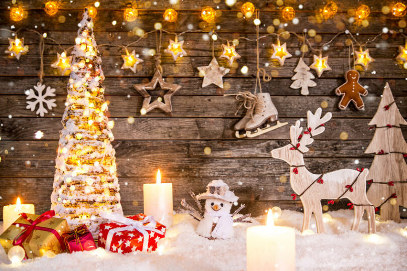 Decoração de Natal toda em miniatura, com árvore iluminada, caixas de presentes, boneco de neve, rena, estrelas e velas.