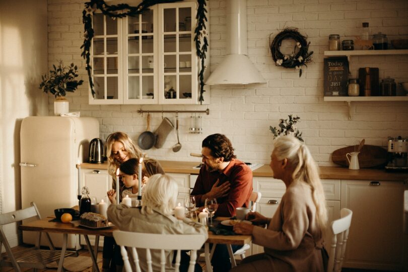 Família sentada ao redor de uma mesa para celebrar a ceia de Natal.