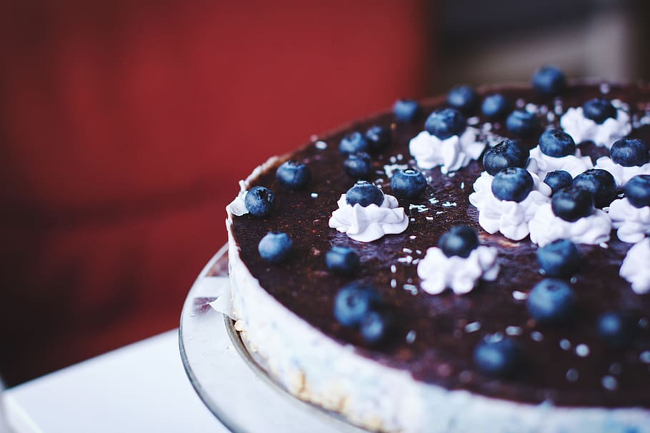 Cheesecake com calda de mirtilo, e mirtilos espalhados em cima.