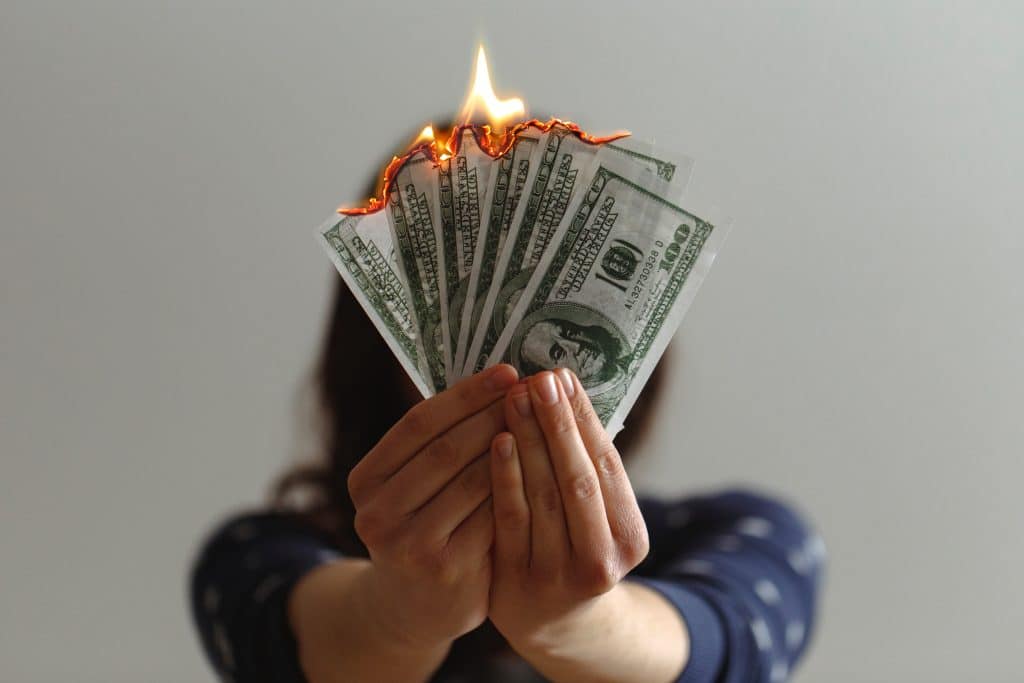 Mulher segurando notas de dólares americanos pegando fogo.