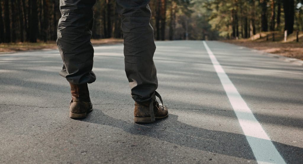 Homem parado no começo de uma estrada, de costas, representando o começo de uma nova jornada.