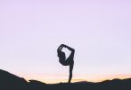 Silhueta de mulher praticando yoga sobre céu arroxeado.