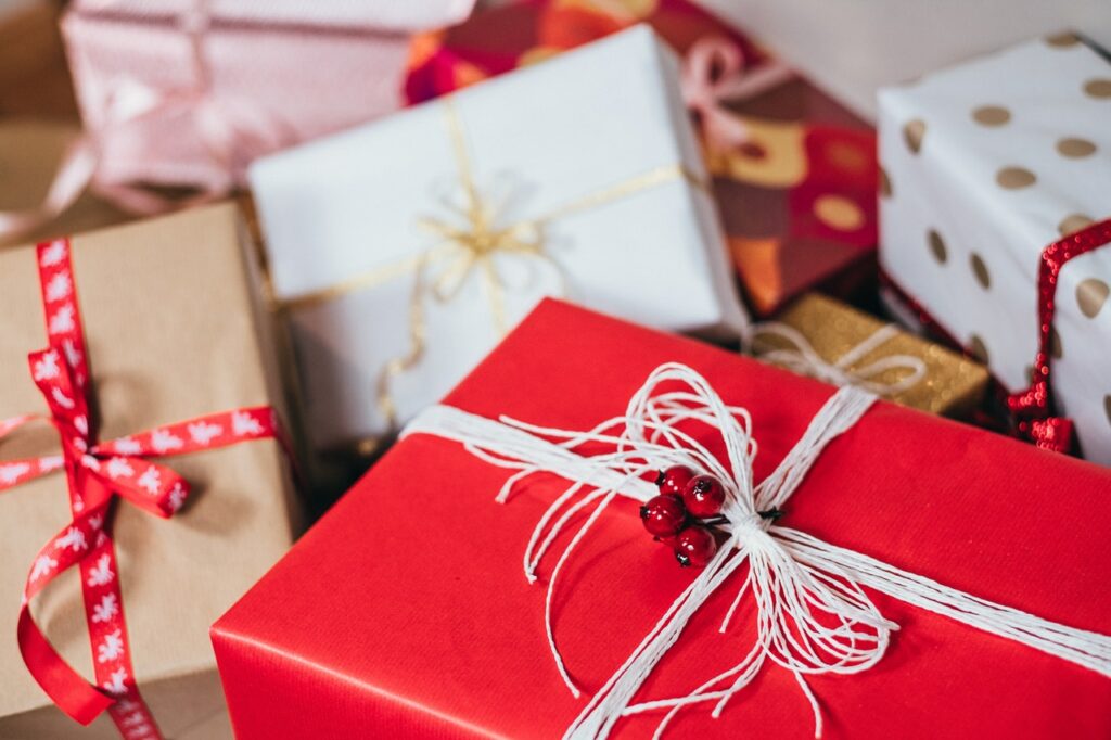 Presentes de Natal embrulhados em papéis de presente de cores diversas como vermelho, branco, bege e rosa.