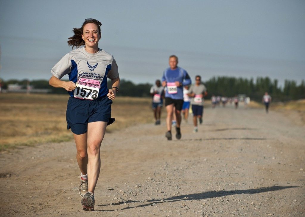 Mulher em uma competição de corrida, correndo com um sorriso no rosto.