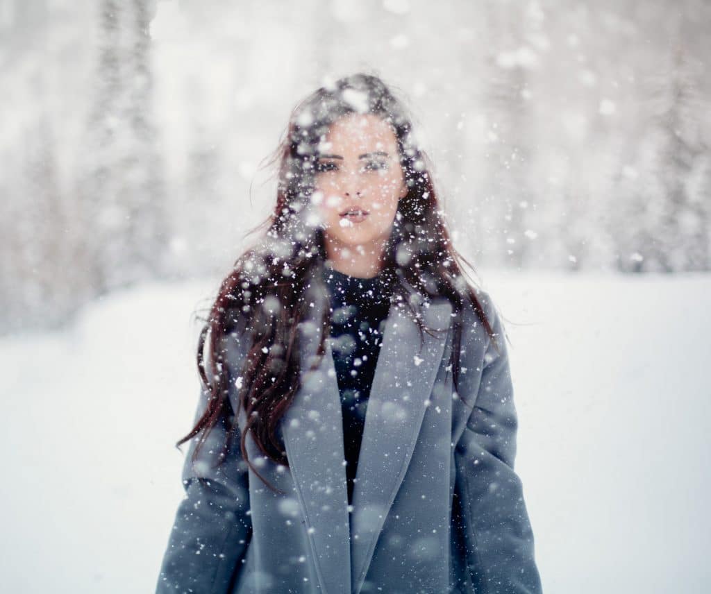 Mulher em pé com flocos de neve caindo