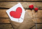 Envelope com uma carta sobre uma mesa de madeira, com um desenho de coração escrito.