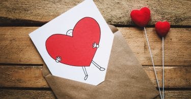 Envelope com uma carta sobre uma mesa de madeira, com um desenho de coração escrito.