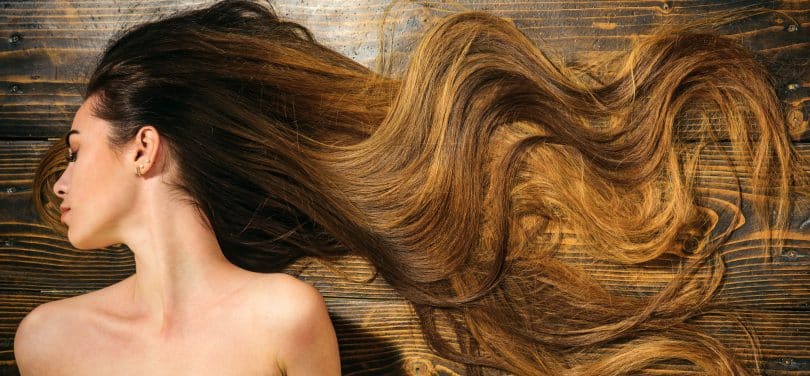 Mulher de cabelos longos sobre cenário de madeira.