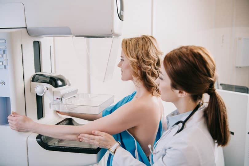 Mulher branca realizando mamografia.