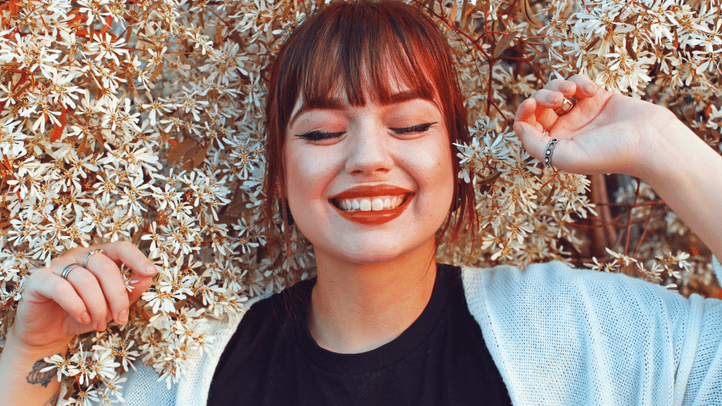 mulher deitada no meio das flores de olhos fechados e sorrindo