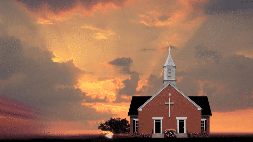 Imagem de uma igreja no meio do campo, ao entardecer.