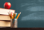 Livros de estudo, maçã e lápis de cor