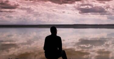 Imagem de um homem refletindo na frente d eum lago