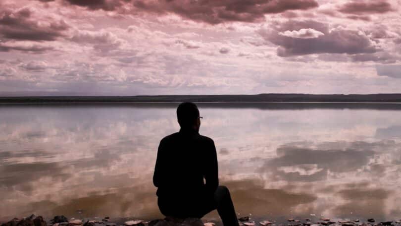 Imagem de um homem refletindo na frente d eum lago