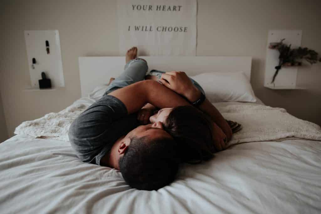 Homem e mulher abraçados e deitados na cama.
