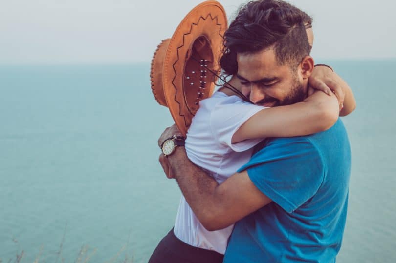 Homem e mulher brancos se abraçando.