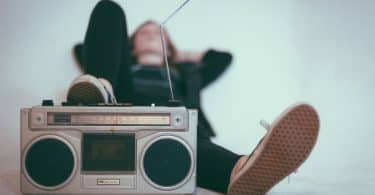 Pessoa deitada no chão com o pé apoiando em um rádio antigo