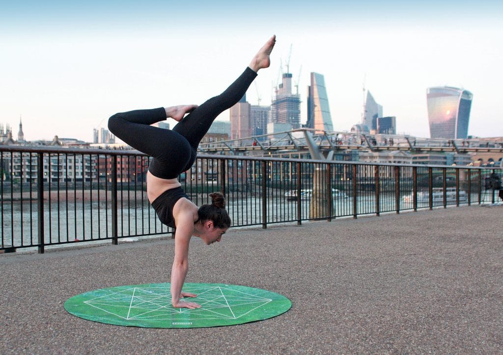 Mulher em posição de Yoga com cidade ao fundo
