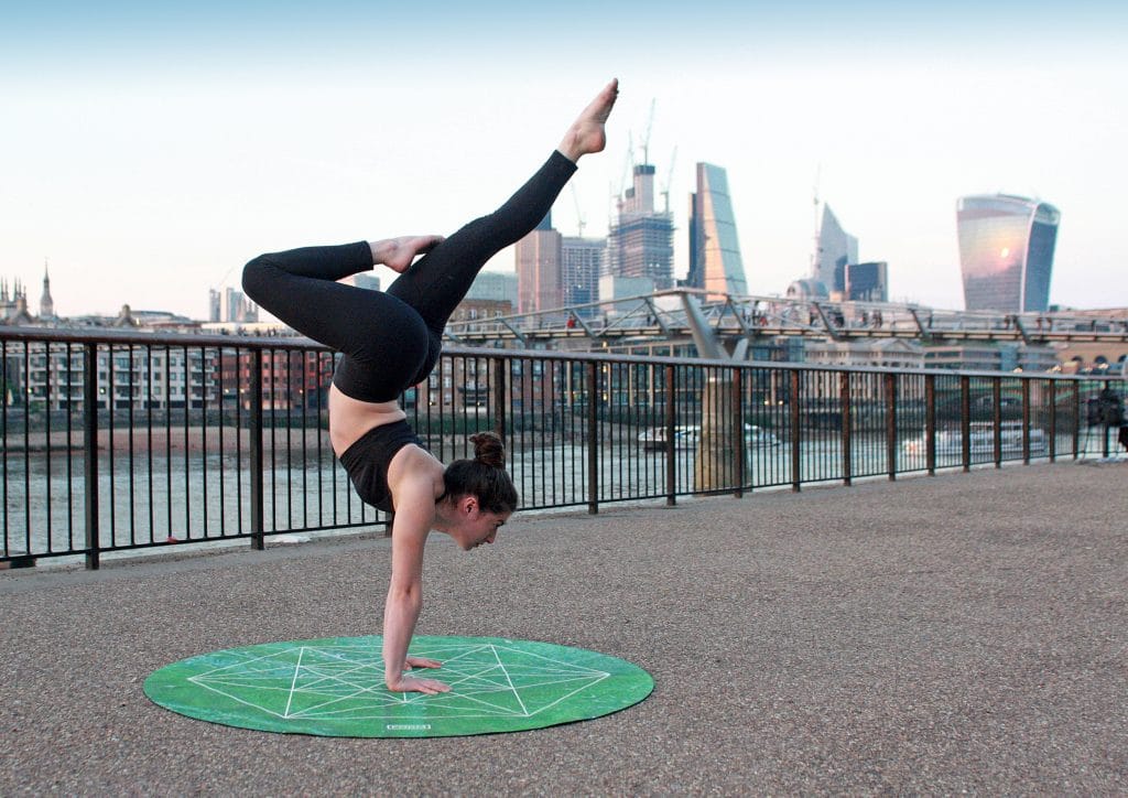 Mulher em posição de Yoga com cidade ao fundo
