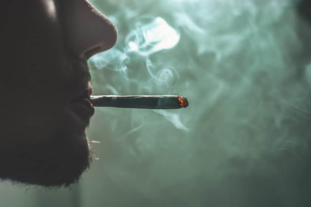 Boca de homem fumando cigarro de maconha