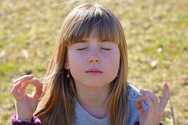 Criança de olhos fechados meditando