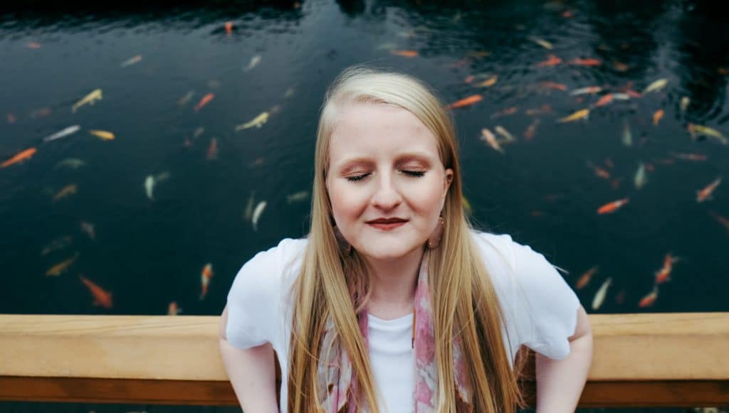 Mulher em ponte de olhos fechados com peixes ao fundo nadando
