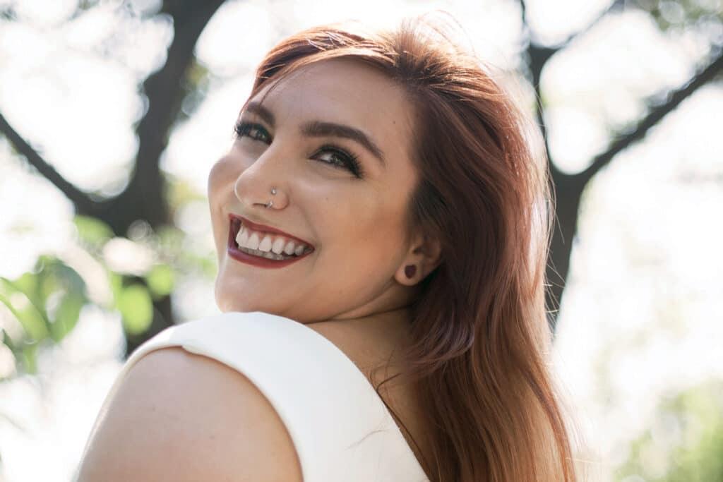 Fotografia de Ju Romano sorrindo em um parque, durante o dia.