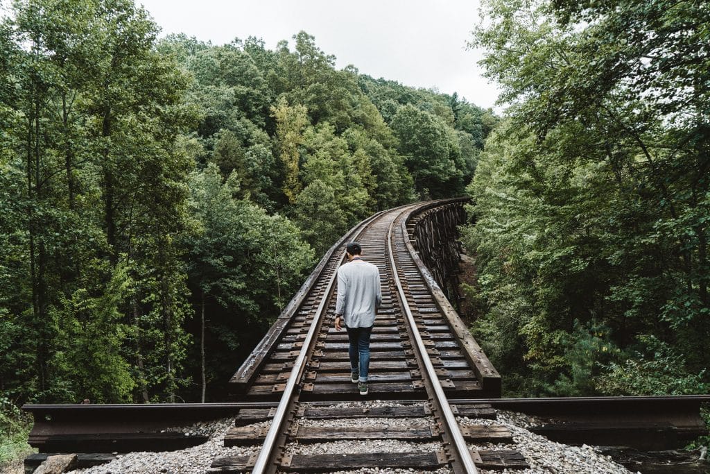 Homem andando nos trilhos de trem