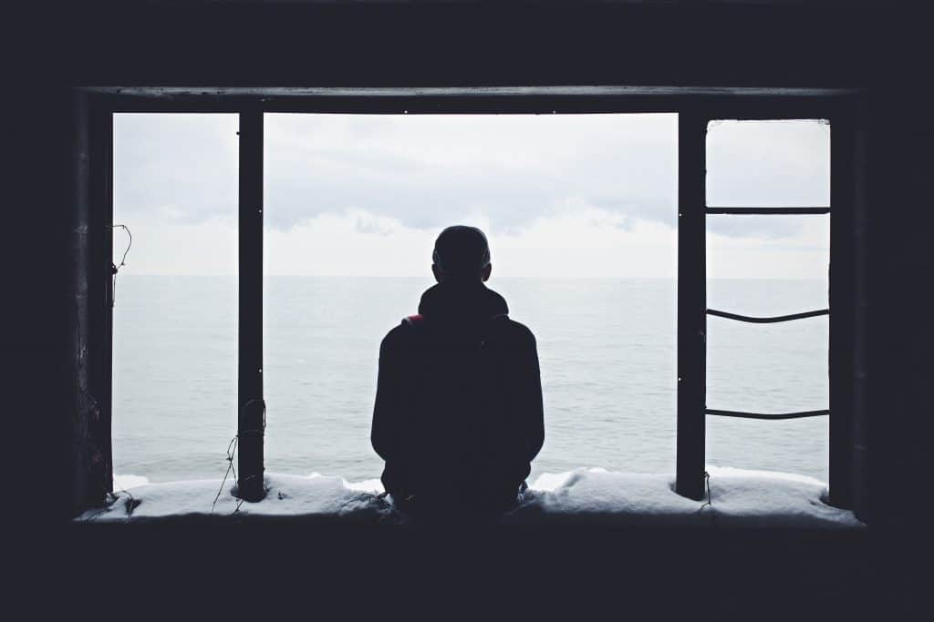 Homem sentado na janela olhando para o horizonte 