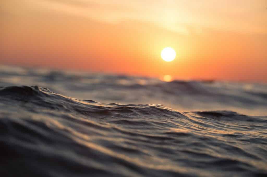 Imagem do mar com o pôr do sol ao fundo.