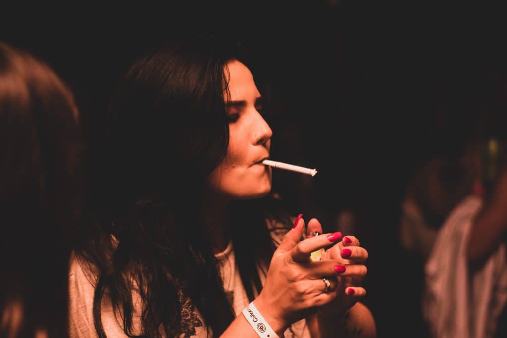 Mulher fumando cigarro segurando isqueiro