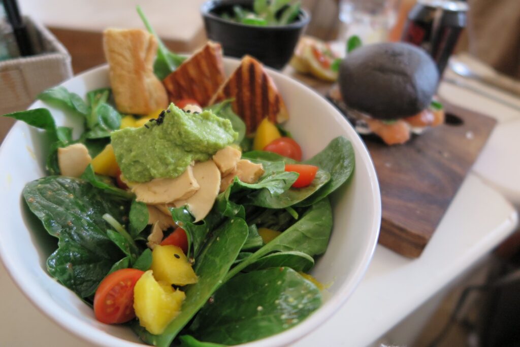 Pasta de espinafre servida com saladas de espinafre, tomates, queijos e torradas.
