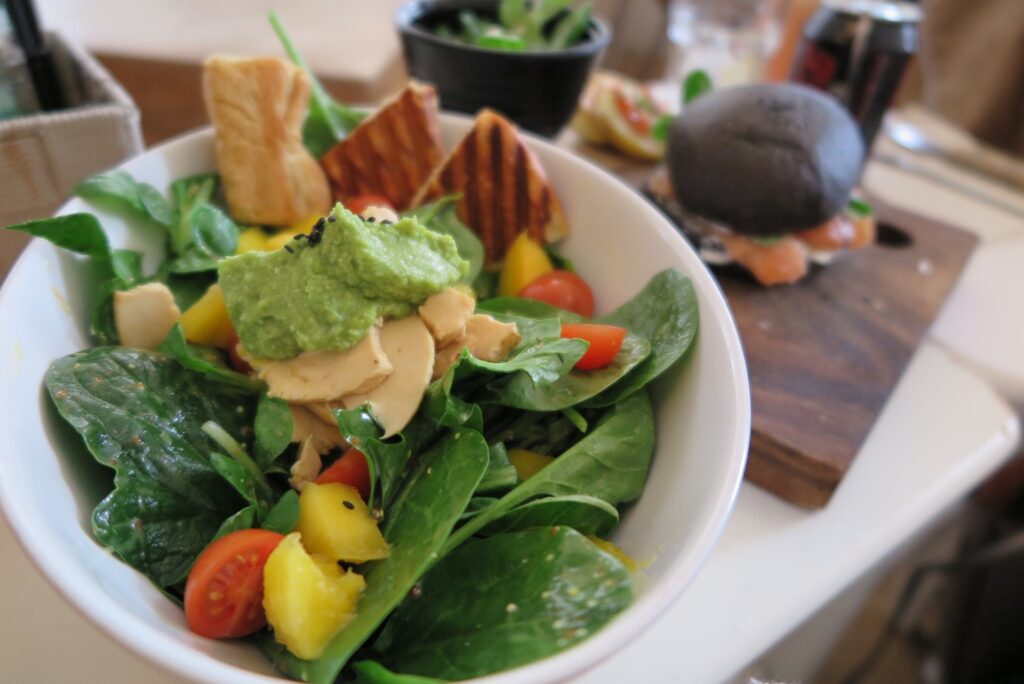 Pasta de espinafre servida com saladas de espinafre, tomates, queijos e torradas.
