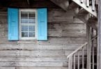 Casa de madeira cinza com janela azul.