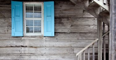 Casa de madeira cinza com janela azul.