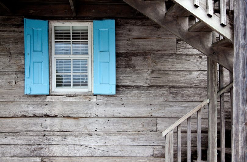 Casa de madeira cinza com janela azul.