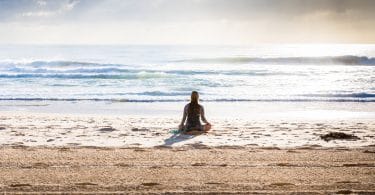 Mulher meditando na praia.