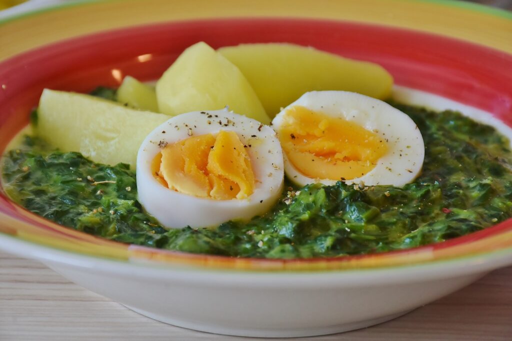 Sopa de espinafre servida com ovos e batatas cozidas.
