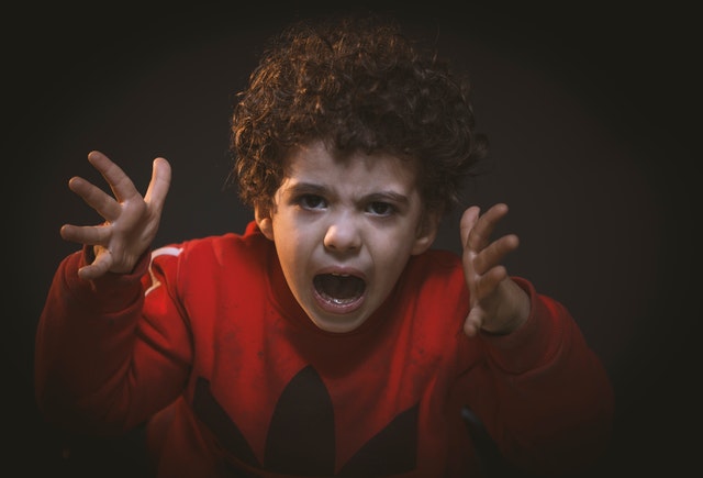 Menino irritado gritando com mãos para o alto